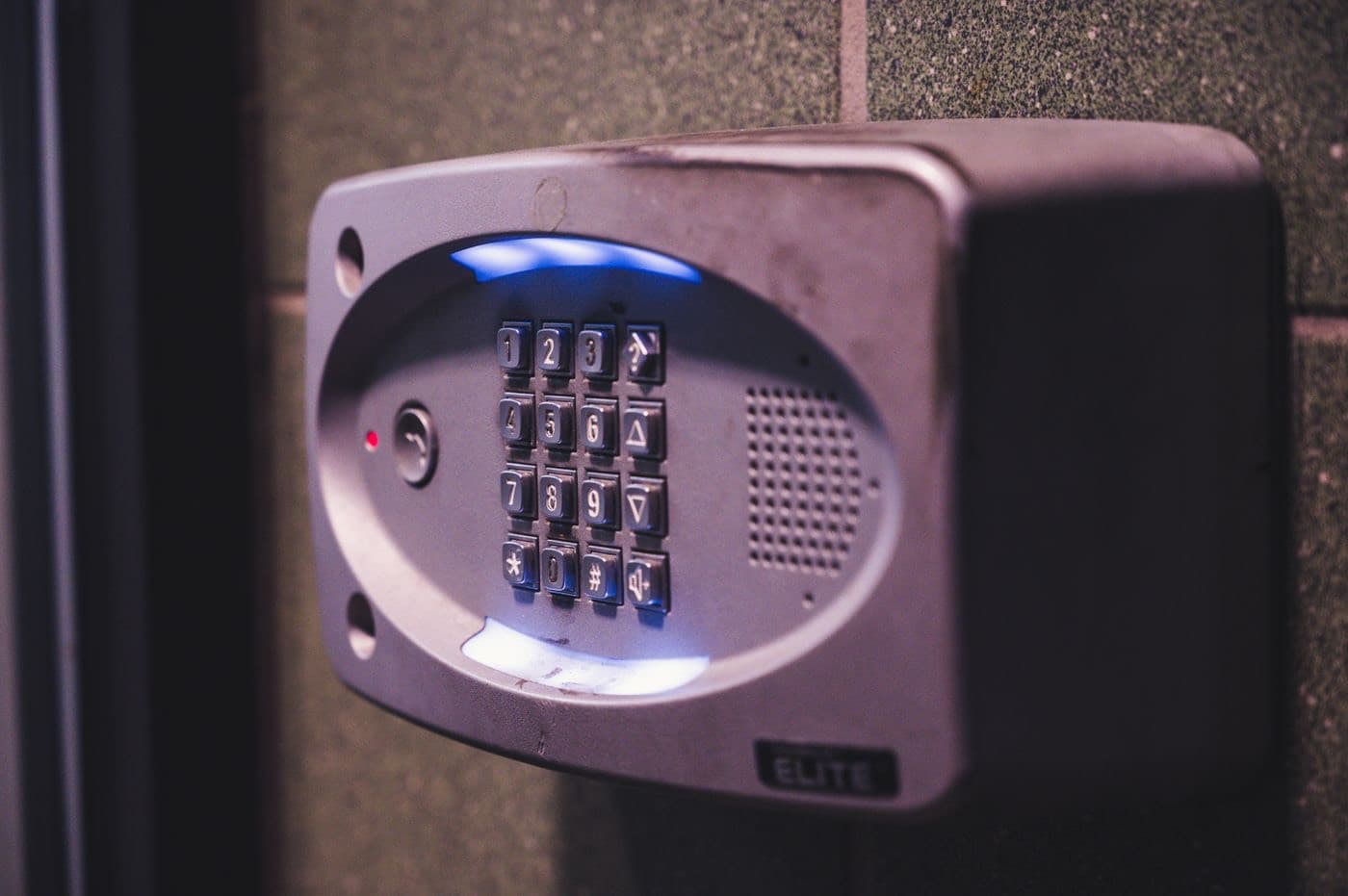 An illuminated security keypad beside a door